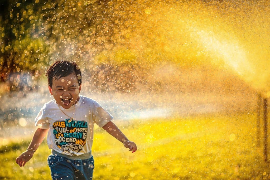 Jongen rent lachend door het water