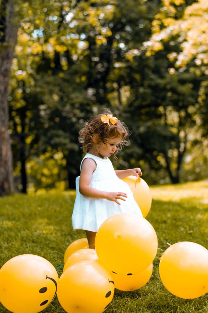 Peuter speelt met ballonnen in het gras