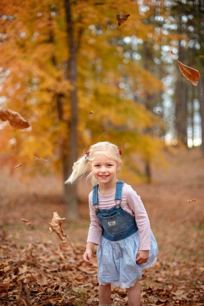 Meisje speelt met herfstbladeren